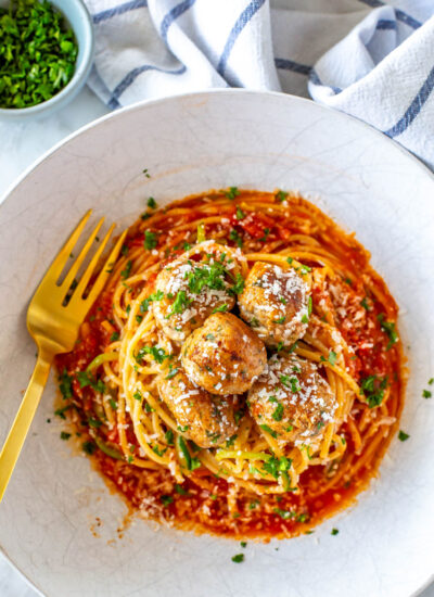 Baked turkey meatballs on a plate of pasta and zucchini.