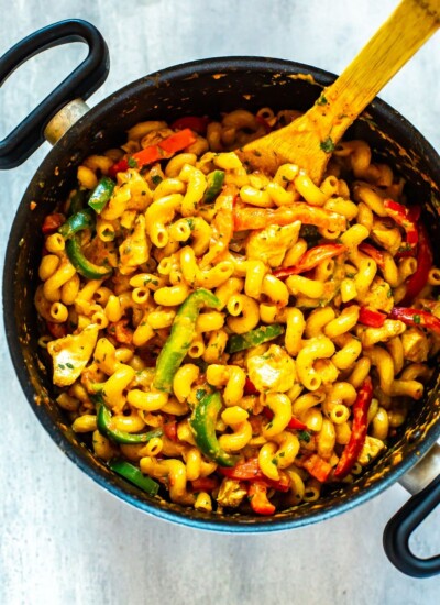 A big pot of cajun chicken pasta with a wooden spoon inside.