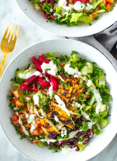 A close-up of a chicken shawarma bowl topped with garlic sauce.