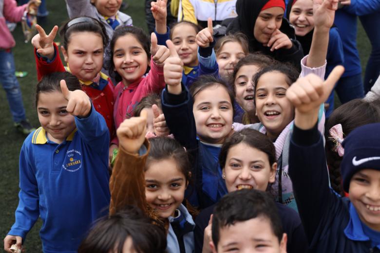 Several children facing the camera and giving a thumbs-up hand gesture