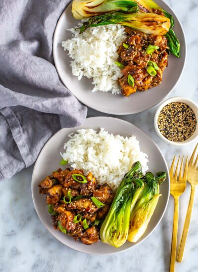 Two plates of ginger chicken served with bok choy and rice.