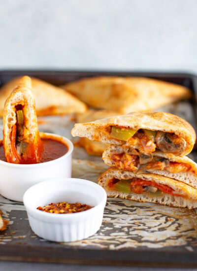 Homemade pizza pockets with a side of red chili flakes and extra marinara