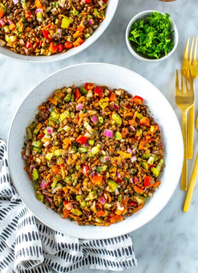 A bowl of lentil salad with a napkin underneath.