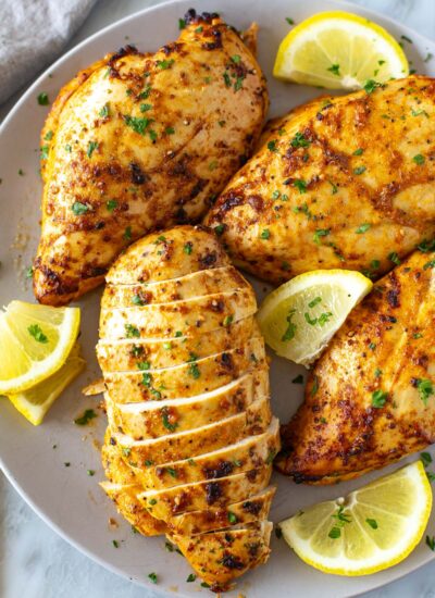 Cooked marinated chicken breasts on a plate.