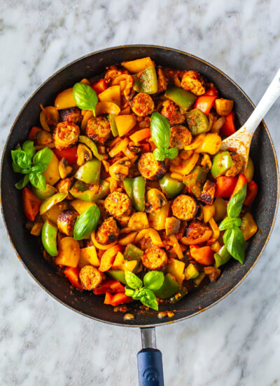 A skillet with sausage, peppers and onions.