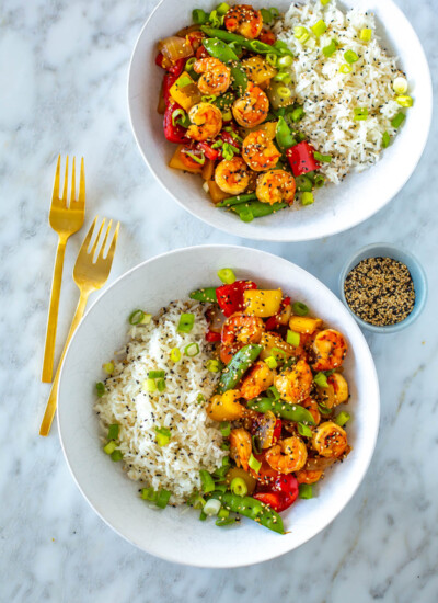 Two bowls, each with a serving of honey garlic shrimp stir fry with a side of rice.