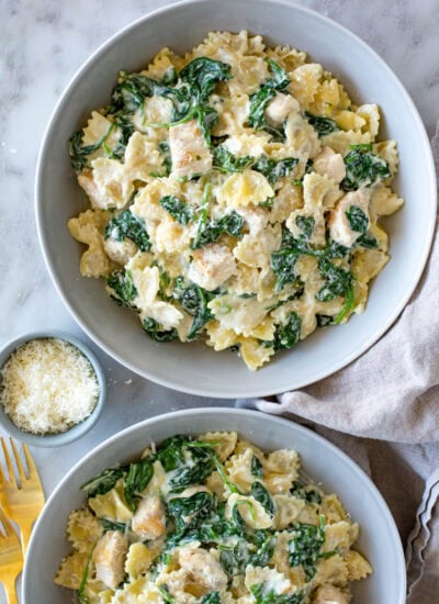 Two bowls of creamy spinach pasta with chicken.