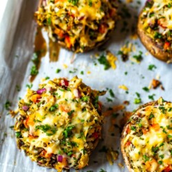 Stuffed portobello mushrooms on a sheet pan lined with parchment paper.